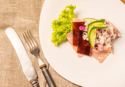 Danish specialties and national dishes, high-quality open sandwich. Sandwich with pork roll sausage, rullepoelse, , jelly and raw red onions, served on a plate ready for eating