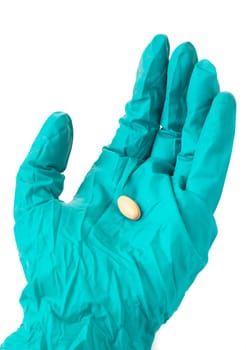 Hand with green protective glove holding an oblong pill, isolated on white background