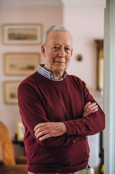 Portrait of a senior man standing with his arms crossed in his home.