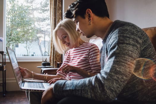 Teenage boy is showing his grandmother how to use a laptop.