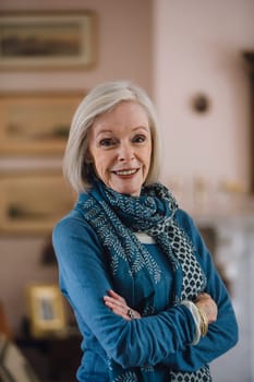 Portrait of a senior woman standing with her arms folded in her home.