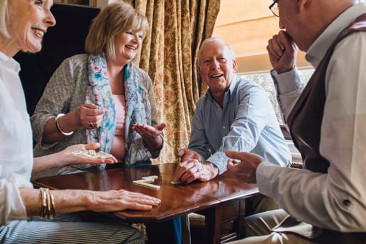 Group of senior friends are playing dominoes at a table together.