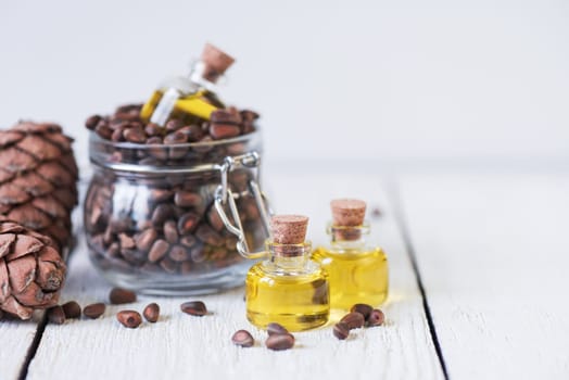 The cedar oil in a glass bottle on a white wooden background. Source of essential fatty acids for healthy nutrition