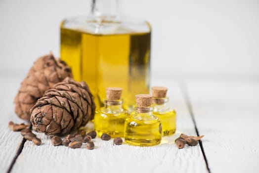 Oil of cedar nuts on a white wooden background
