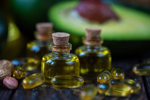 Oil of avocado with fish oil pills and peanut - source of omega 3 on a dark wooden background