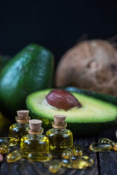 Oil of avocado with fish oil pills and peanut - source of omega 3 on a dark wooden background
