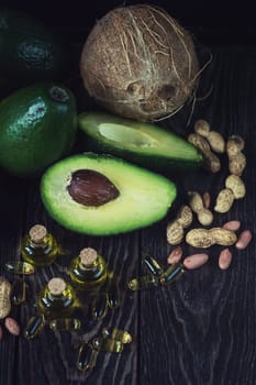 Oil of avocado with fish oil pills and peanut - source of omega 3 on a dark wooden background