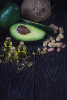Oil of avocado with fish oil pills and peanut - source of omega 3 on a dark wooden background