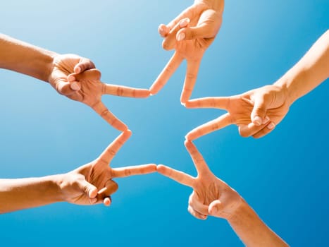 Friends making a star with fingers against the sky