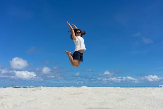 Woman jumping on the sand of the beach