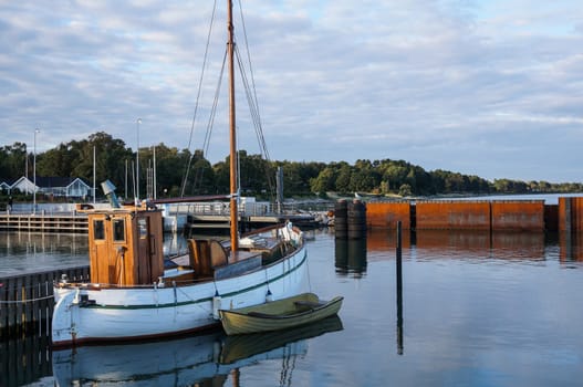 Harbor with little blue fisherboat with bright blue sky