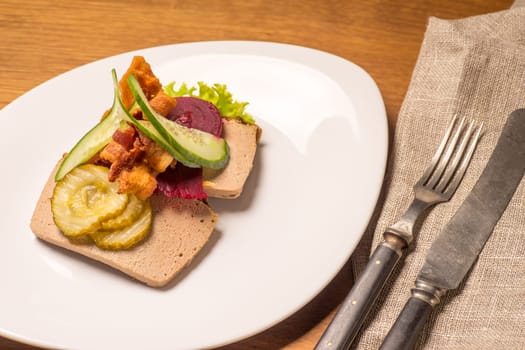 Danish specialties and national dishes, high-quality open sandwich, Liver Pate with bacon pickled cucumber, beetroot and cucumber served on a plate ready for eating