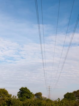 electric wires on a pylon in the distance spreading across the clear blue and cloudy sky beautiful communication peace