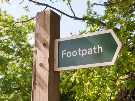 a sign on a wooden post saying footpath for walking outside in country close up english uk wayfaring directions for public use