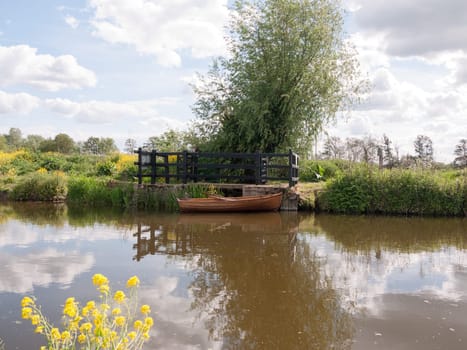 a wooden boat moored and parked on a river in the countryside of essex in the uk and england with no people beautiful and peaceful boating travel