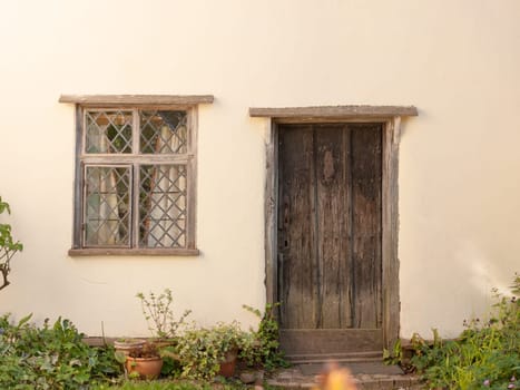 an old fashioned door and window of a cottage in england essex of the uk outside very clean and white made of wood and brick front garden peace