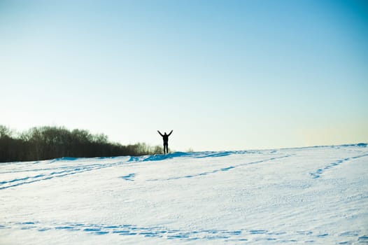 man in warm clothes with a beard is walking on the street in the winter in a warm sunny day at the river against the sky, jumping up and running in the snow