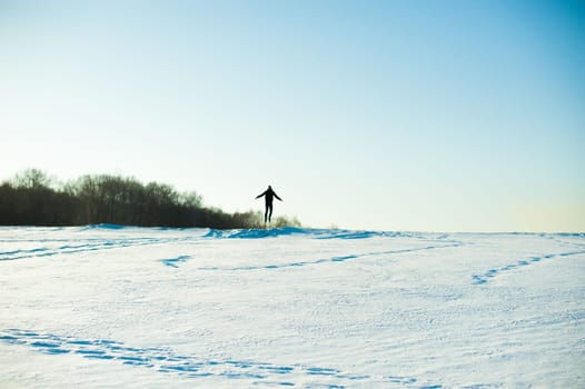 man in warm clothes with a beard is walking on the street in the winter in a warm sunny day at the river against the sky, jumping up and running in the snow