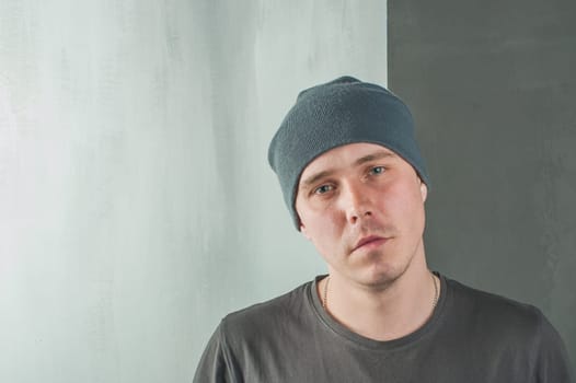 studio photography of a young man in a gray T-shirt and cap. Portrait of a Man looking at the camera, in the middle of the two backgrounds, Lightstone and dark