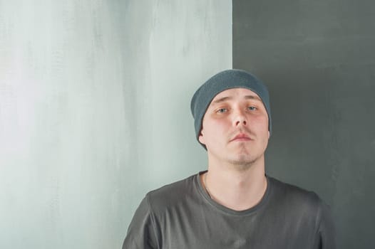 studio photography of a young man in a gray T-shirt and cap. Portrait of a Man looking at the camera, in the middle of the two backgrounds, Lightstone and dark