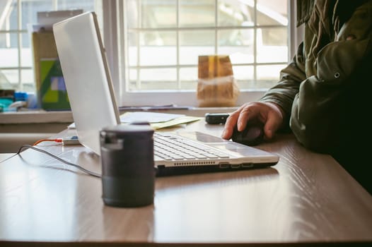 adult man with a mustache and glasses, working at a computer, holding a mouse in their hands.