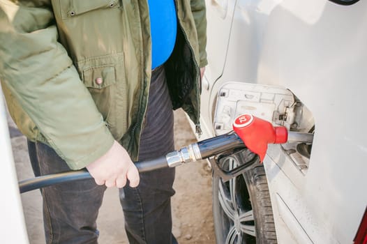 man at a gas station fills the fuel in the vehicle tank