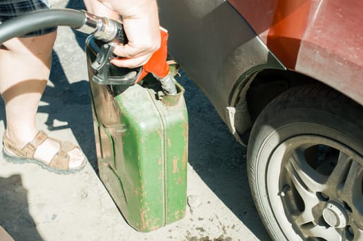 man at a gas station fills the fuel in the vehicle tank