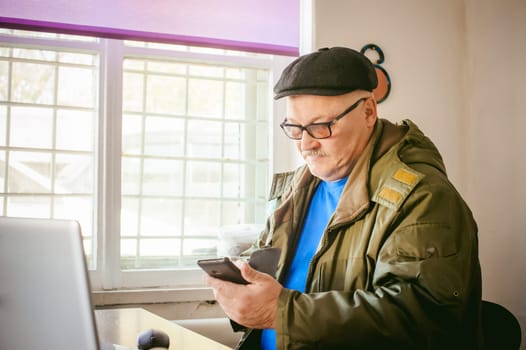 adult man with a mustache and glasses, working at a computer, holding a mouse in their hands.