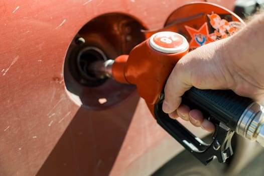 man at a gas station fills the fuel in the vehicle tank