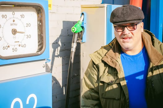 man at a gas station fills the fuel in the vehicle tank. adult man with a mustache and glasses, fueling car before a long journey on the road to non-network gas station
