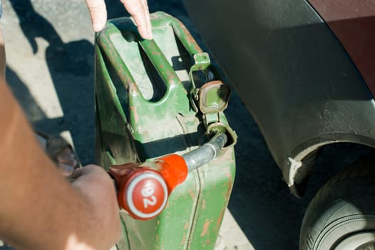 man at a gas station fills the fuel in the vehicle tank