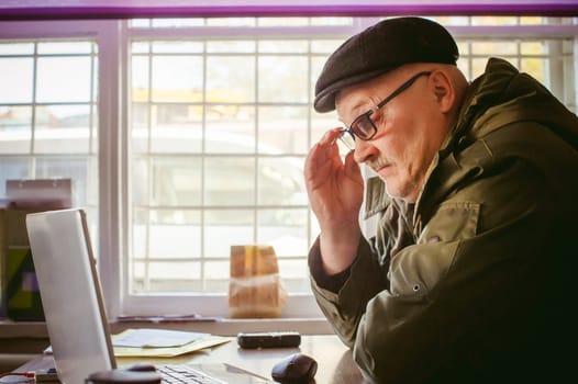 adult man with a mustache and glasses, working at a computer, holding a mouse in their hands.
