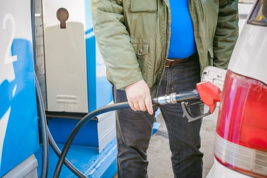 man at a gas station fills the fuel in the vehicle tank