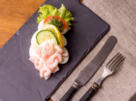 Danish specialties and national dishes, high-quality open sandwich. Boiled Egg, Shrimps, mayo, cucumber and lemon served on a plate and ready for eating