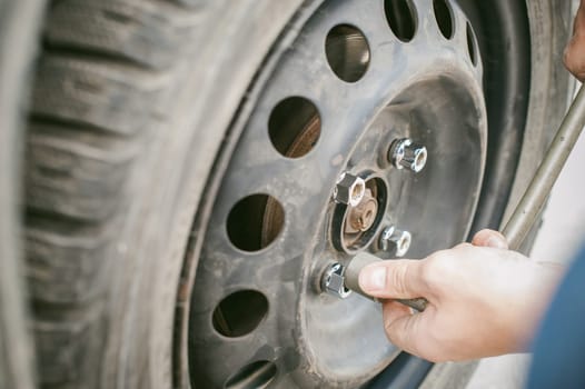 man changing a wheel on the road. on way there was breakage of wheel, puncture, necessary to lift the car jack and remove the wheel by loosening the nuts. road problems travelers. do it yourself