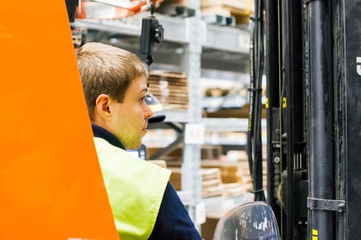 young man in working clothes, driver Reachtruck busy working on the logistics warehouse store