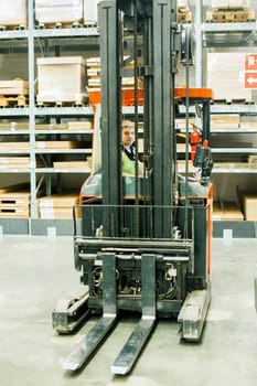 young man in working clothes, driver Reachtruck busy working on the logistics warehouse store