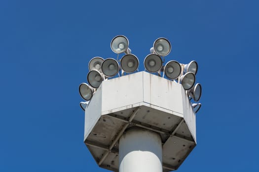 Many speakers on high tower against a clear sky background..