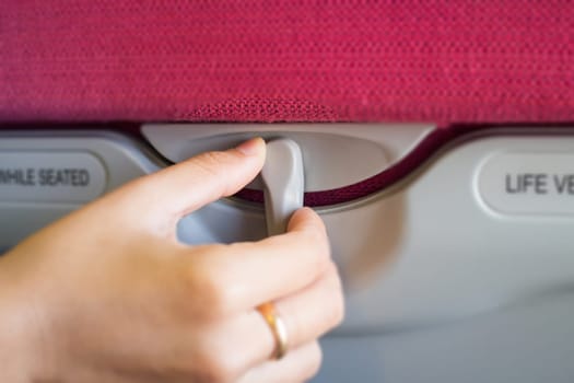 Hand On Hidden Table Of Airplane Seat, stock photo