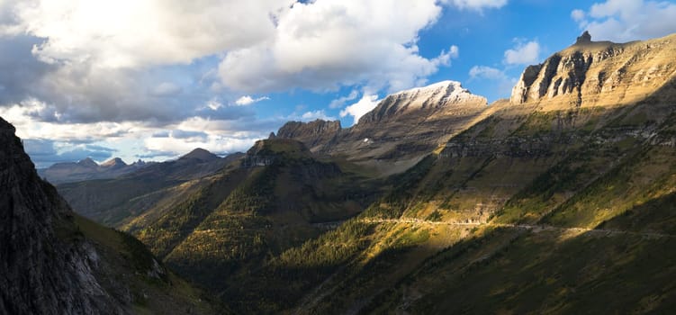 High peaks of the rocky mountains loom over the highway in Glacier National Park