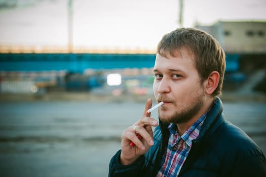 cigarette smoking. a man with a beard smokes a cigarette on the street in a public place.
