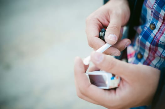 man pulls a cigarette from the pack and lights up.