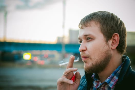 cigarette smoking. a man with a beard smokes a cigarette on the street in a public place.
