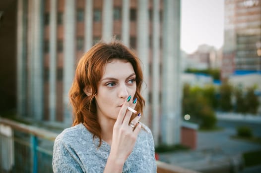 girl with a cigarette. young beautiful woman smokes a cigarette in the street