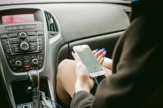 girl holding a phone. mobile in female hands, a woman chooses to music through the app in a smartphone connected to the car's audio system