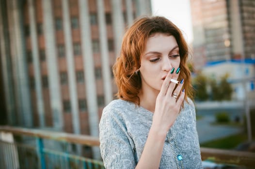 girl with a cigarette. young beautiful woman smokes a cigarette in the street
