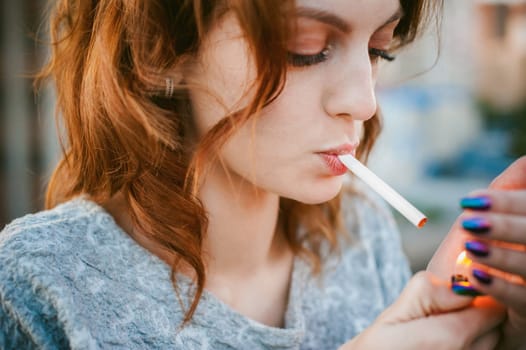 girl with a cigarette. young beautiful girl smokes a cigarette on the street. ignites the lighter, lighting his tobacco