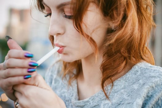 girl with a cigarette. young beautiful girl smokes a cigarette on the street. ignites the lighter, lighting his tobacco