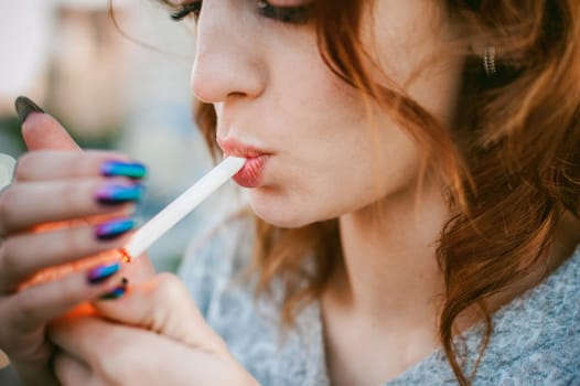 girl with a cigarette. young beautiful girl smokes a cigarette on the street. ignites the lighter, lighting his tobacco