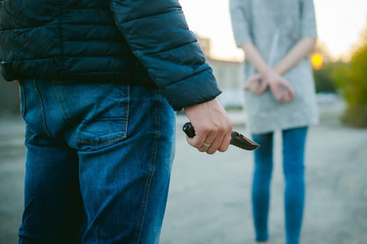 a guy with a knife chasing a girl. Man with a gun in his hand catches up with the young wife of connectedness with hands behind his back.